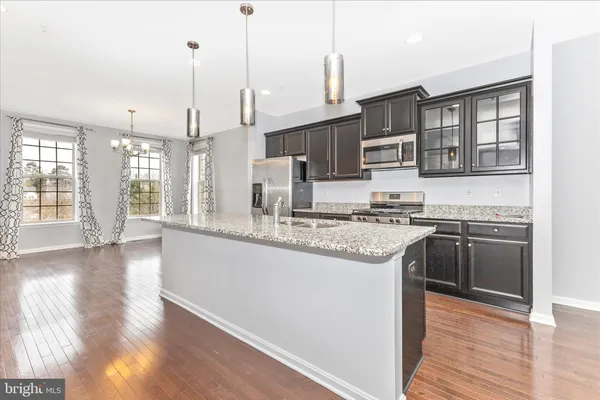 a kitchen with stainless steel appliances granite countertop a stove and a wooden floor