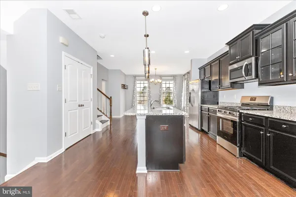 a large kitchen with stainless steel appliances granite countertop a stove top oven a sink dishwasher and wooden floor