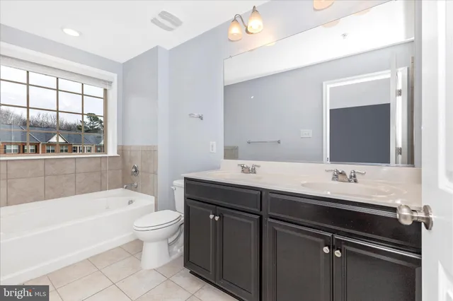 a bathroom with a double vanity sink toilet mirror and bathtub