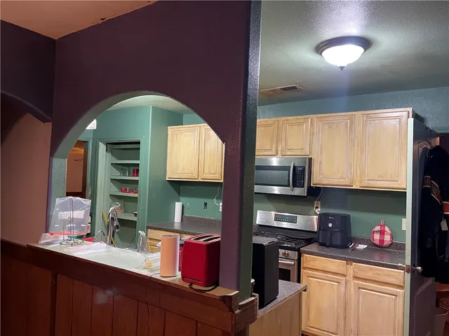 a kitchen with granite countertop wooden cabinets stainless steel appliances and a sink