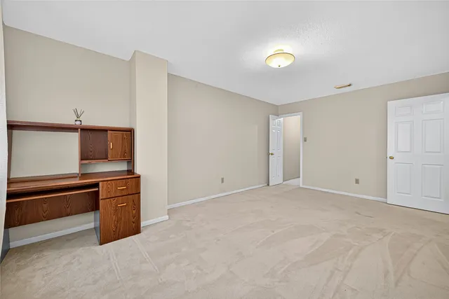 a view of an empty room with kitchen and window