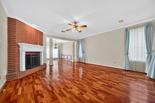 a view of an empty room with wooden floor fireplace and a window