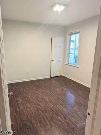 an empty room with wooden floor and window