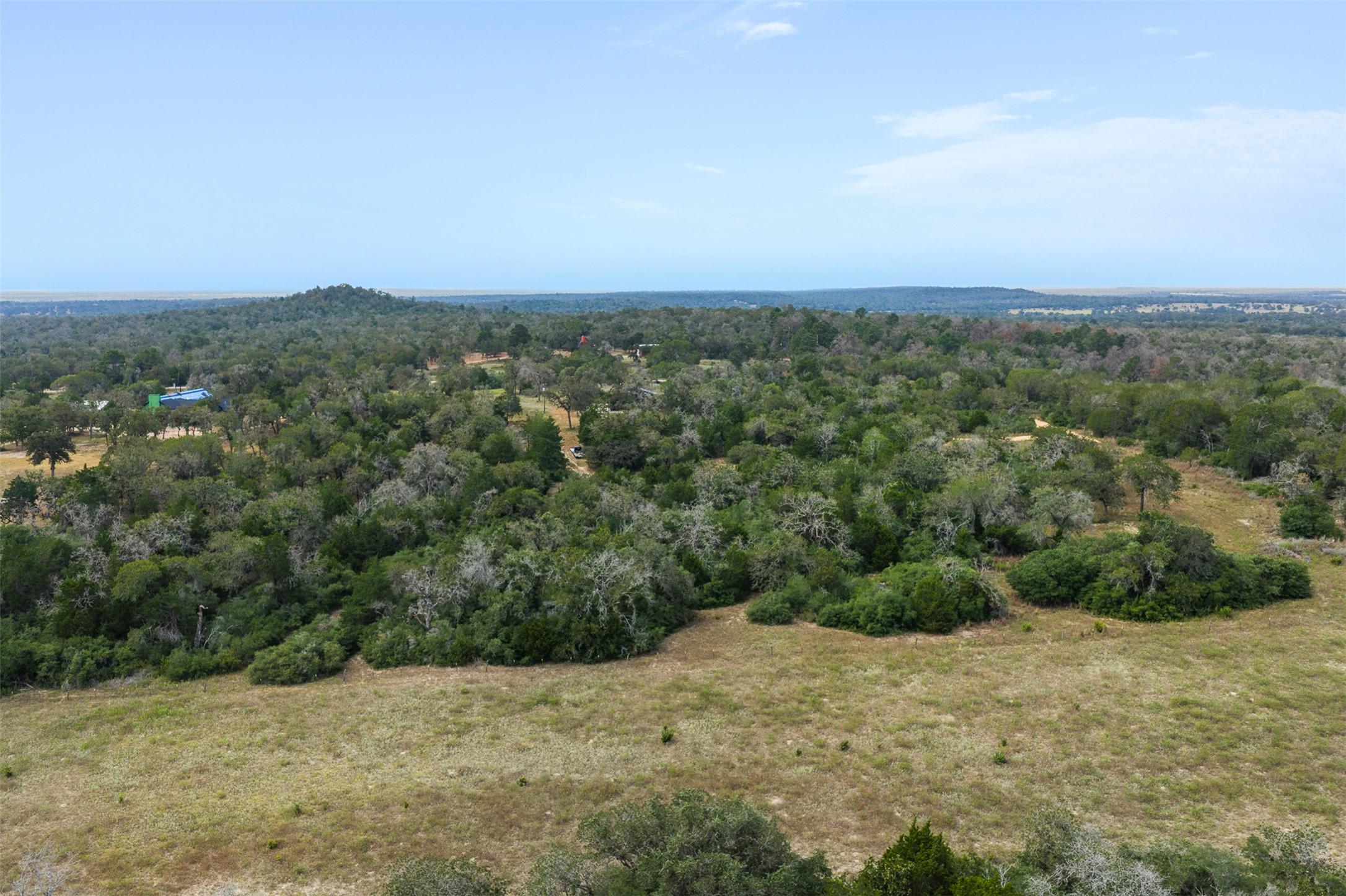 3301 Chuckwagon Road Harwood, TX 78632 - Photo 28 of 36 Mature woodlands and open clearings stretch across the rolling landscape under broad blue skies.