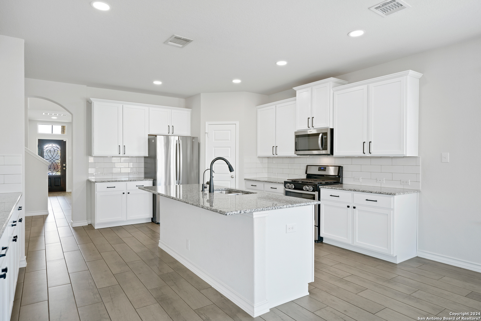 648 Amber Creek Cibolo, TX 78108 - Photo 12 of 34 a large kitchen with stainless steel appliances granite countertop a stove top oven a sink a refrigerator and white cabinets with wooden floor