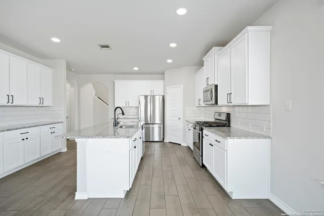 a kitchen with white cabinets appliances and sink