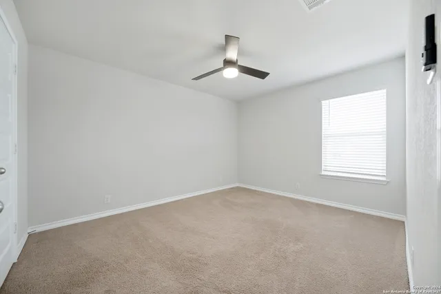 an empty room with a window and ceiling fan
