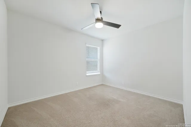an empty room with a window and a fan