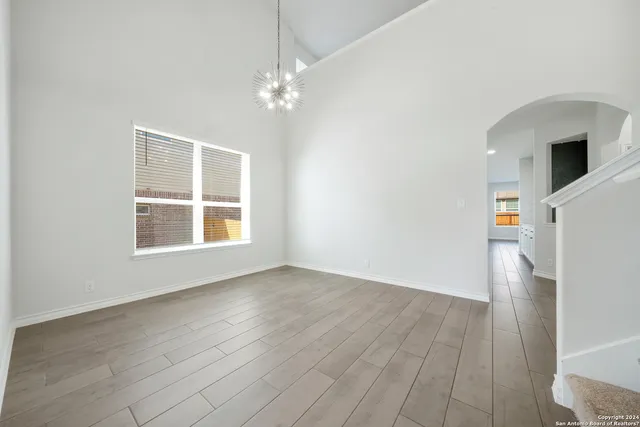an empty room with wooden floor cabinet and windows