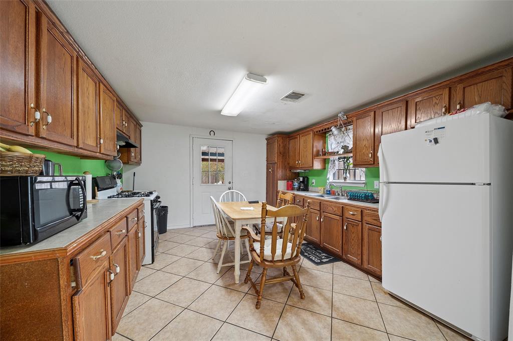 1917 Bell Street Waco, TX 76711 - Photo 7 of 17 a kitchen with granite countertop a refrigerator a stove a sink a dining table and chairs with wooden floor