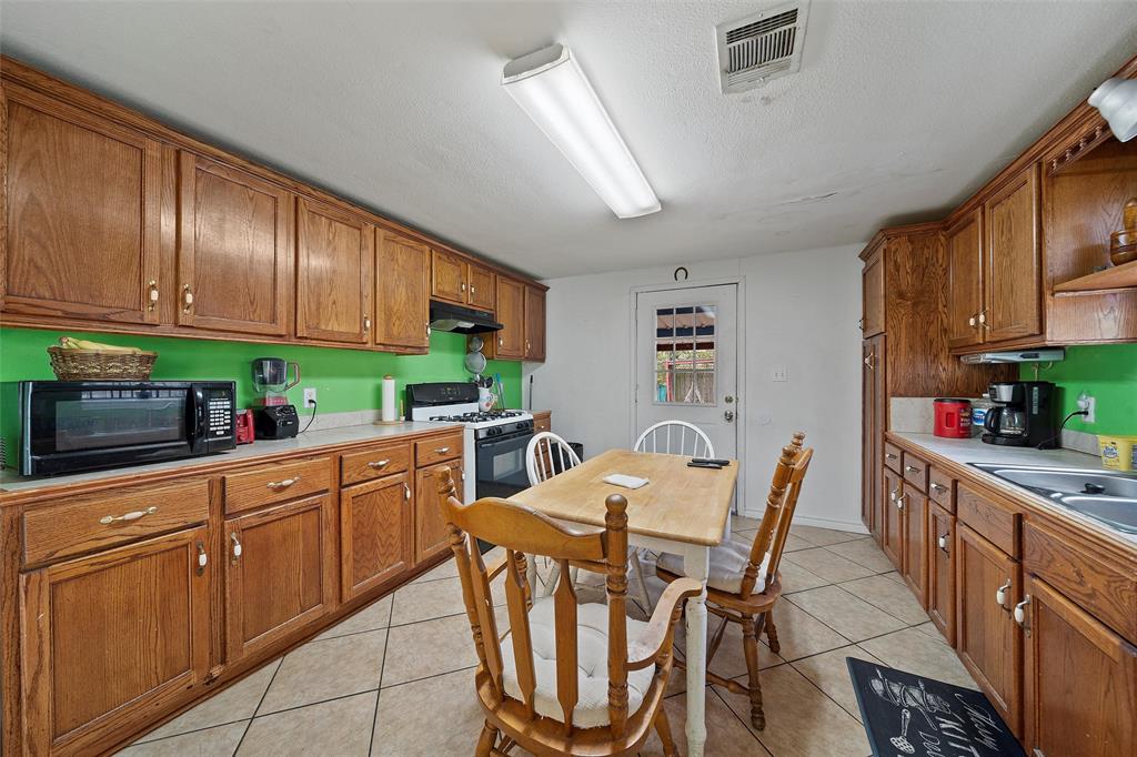 1917 Bell Street Waco, TX 76711 - Photo 8 of 17 a kitchen with stainless steel appliances kitchen island granite countertop a table chairs in it and a window