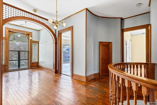a view of a livingroom with wooden floor a ceiling fan and windows