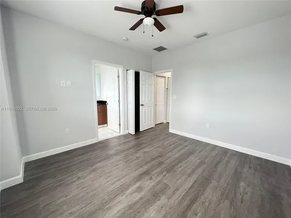 an empty room with wooden floor and ceiling fan
