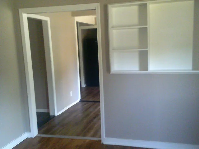 a view of an empty room with wooden floor and a window