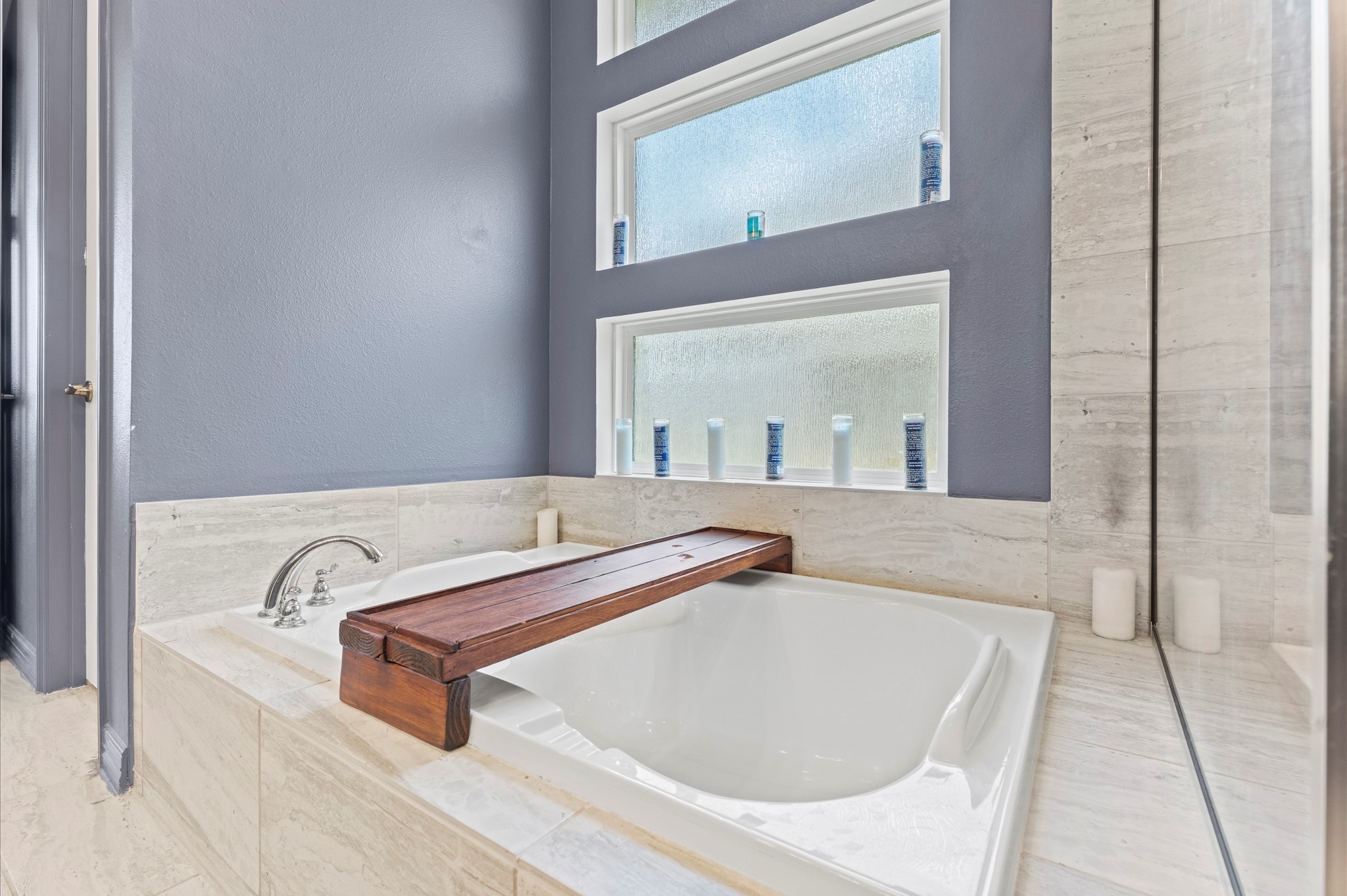 3510 Whitman Drive Rosharon, TX 77583 - Photo 11 of 25 This bathroom features a luxurious soaking tub with sleek fixtures, surrounded by elegant tile. A wall with frosted windows allows natural light while maintaining privacy.