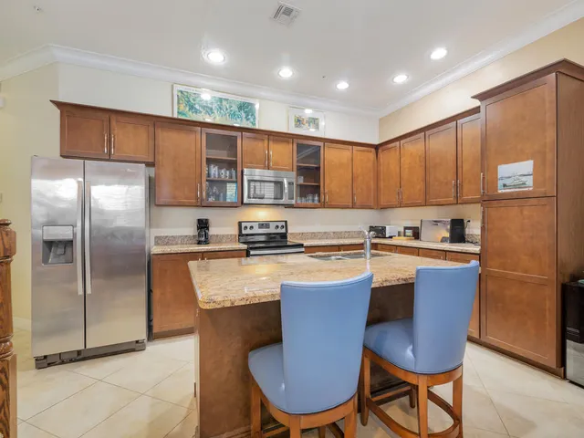 a kitchen with stainless steel appliances granite countertop a refrigerator a sink a stove a dining table and chairs