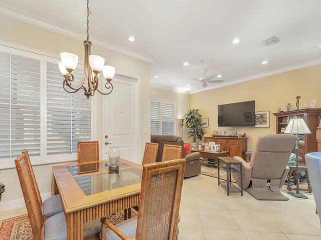 a dining room with wooden floor a chandelier a glass table and chairs