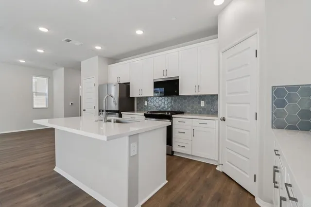 a large kitchen with stainless steel appliances a refrigerator and a stove top oven