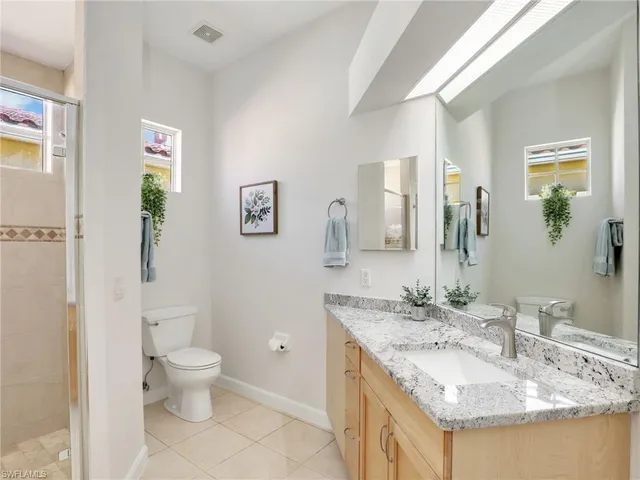 a bathroom with a granite countertop sink a toilet and a mirror
