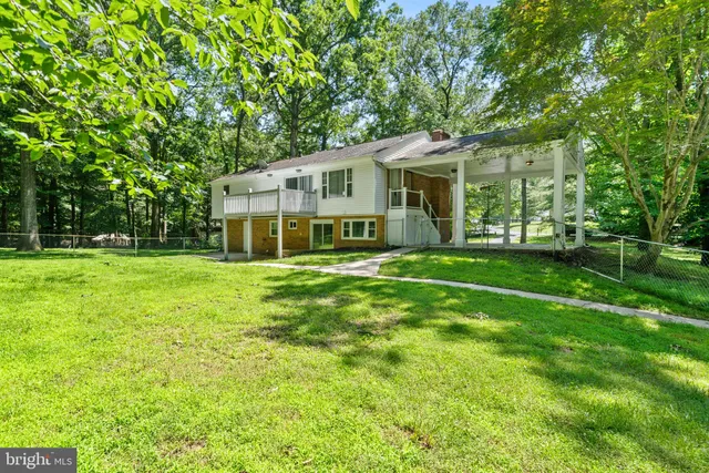 a view of a house next to a big yard and large trees