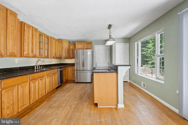 a kitchen with stainless steel appliances granite countertop wooden floors a stove top oven a sink with wooden floor and cabinets