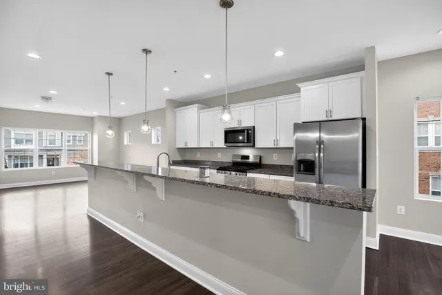 a large kitchen with granite countertop a large counter top appliances and cabinets