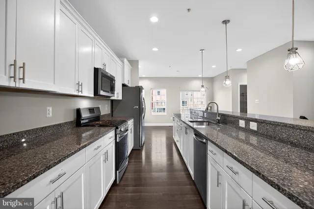 a kitchen with granite countertop a sink a counter top space stainless steel appliances and cabinets