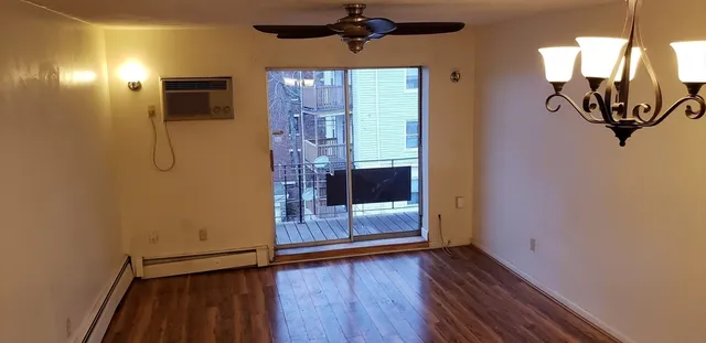 a view of a hallway with wooden floor and a bathroom
