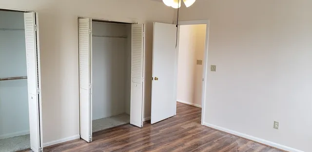 an empty room with wooden floor and a hallway
