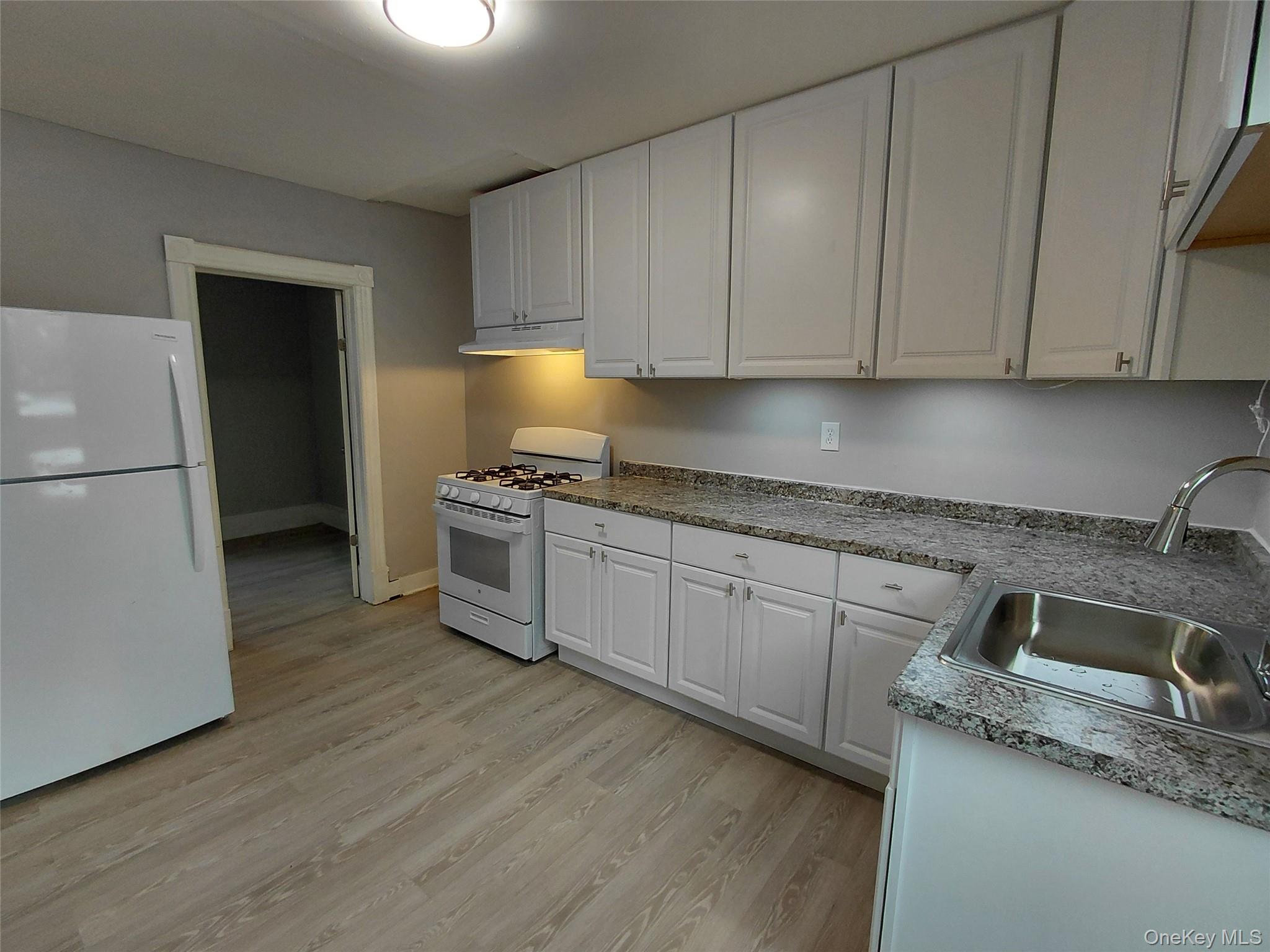 67 Greenkill Avenue, Unit A2 Kingston, NY 12401 - Photo 3 of 13 Kitchen with white appliances, white cabinets, light wood finished floors, and light countertops