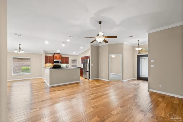 a view of a kitchen with kitchen island stainless steel appliances wooden floor and living room view
