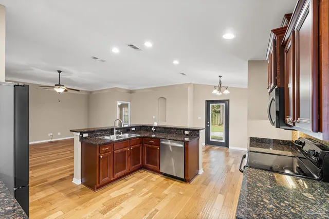 a kitchen with stainless steel appliances granite countertop a stove top oven a sink a dining table and chairs