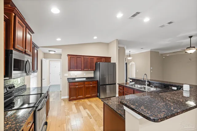 a kitchen with stainless steel appliances kitchen island granite countertop a refrigerator and a stove top oven