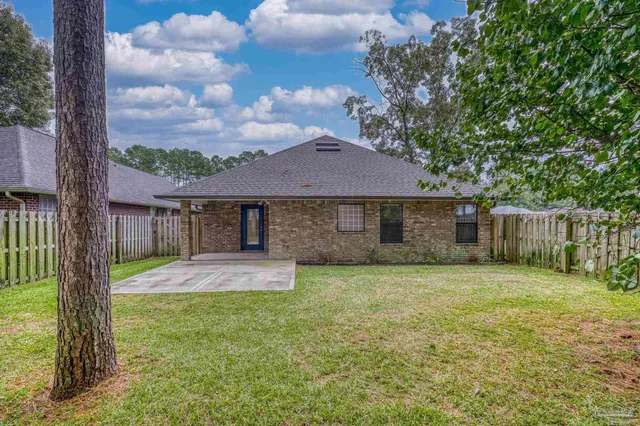 a view of a backyard with large trees and wooden fence