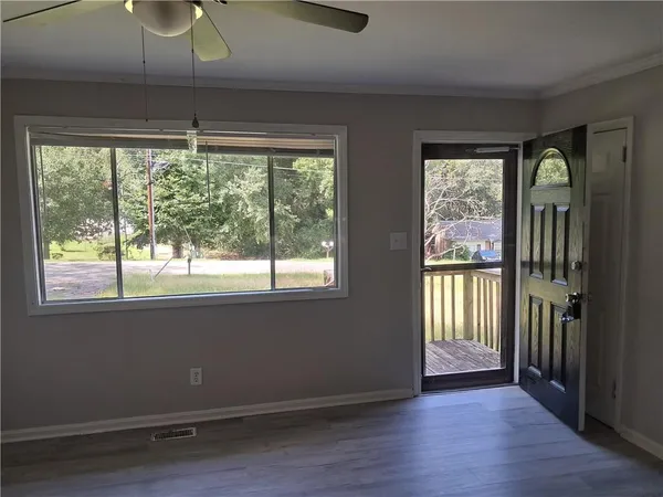 a view of an empty room with wooden floor and a window