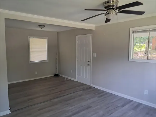 a view of an empty room with wooden floor and a window