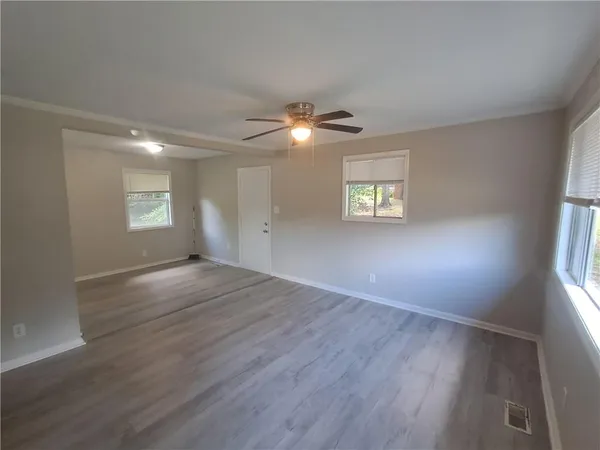 a view of an empty room with a window and wooden floor