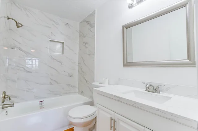 a bathroom with a granite countertop sink a toilet and bathtub