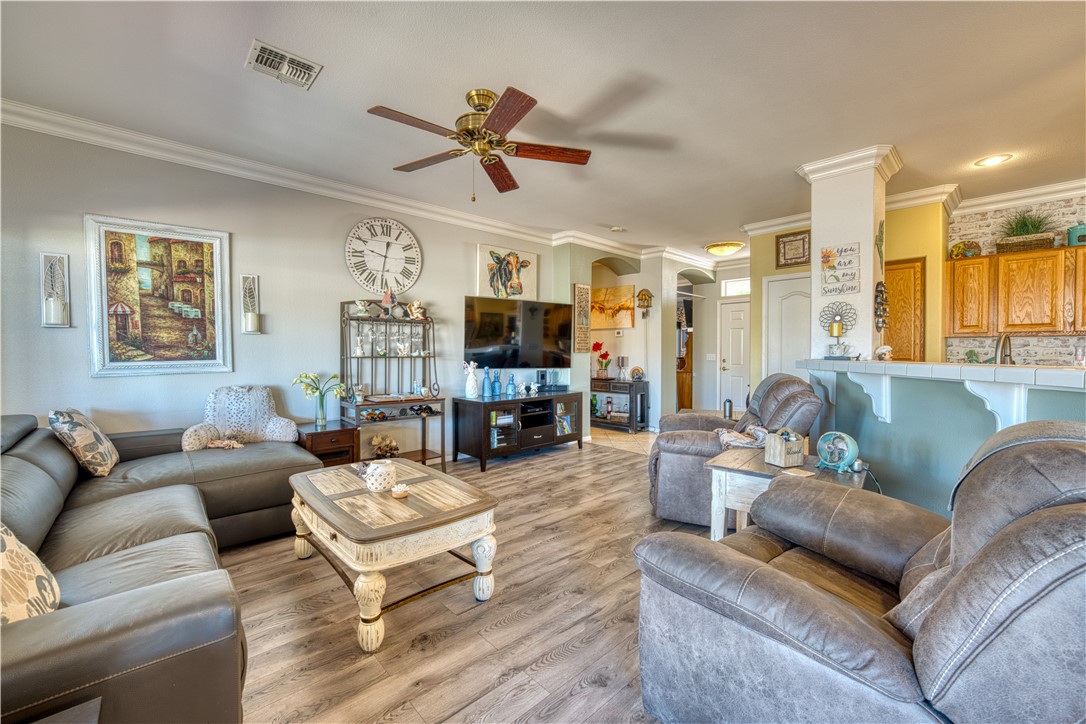 2341 Half Moon Way Bullhead City, AZ 86442 - Photo 16 of 35 Living room featuring crown molding, wood finished floors, and a ceiling fan
