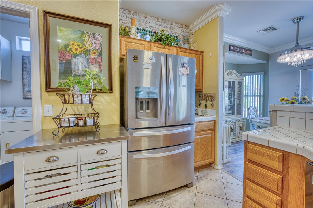 2341 Half Moon Way Bullhead City, AZ 86442 - Photo 20 of 35 Kitchen featuring stainless steel fridge, plenty of natural light, ornamental molding, light tile patterned floors, and tasteful backsplash