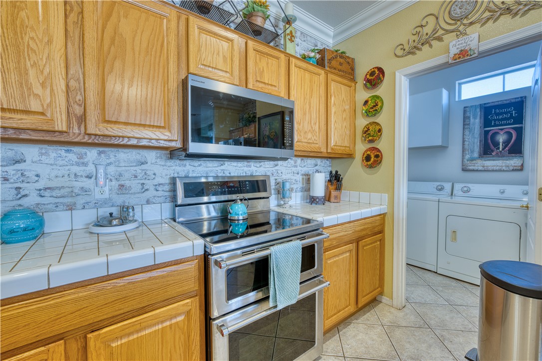 2341 Half Moon Way Bullhead City, AZ 86442 - Photo 21 of 35 Kitchen with appliances with stainless steel finishes, tile countertops, tasteful backsplash, crown molding, and light tile patterned floors