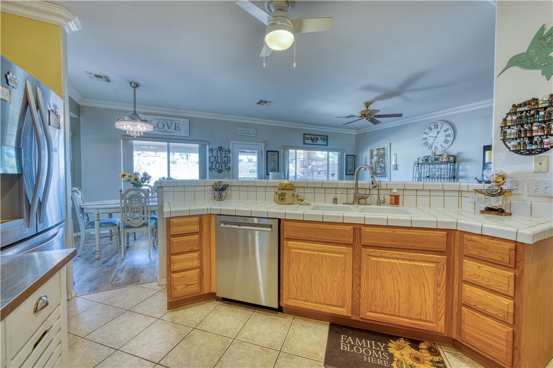 2341 Half Moon Way Bullhead City, AZ 86442 - Photo 22 of 35 Kitchen with tile countertops, brown cabinets, crown molding, and stainless steel appliances