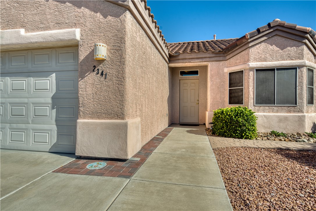 2341 Half Moon Way Bullhead City, AZ 86442 - Photo 3 of 35 Doorway to property featuring stucco siding, a tile roof, and a garage