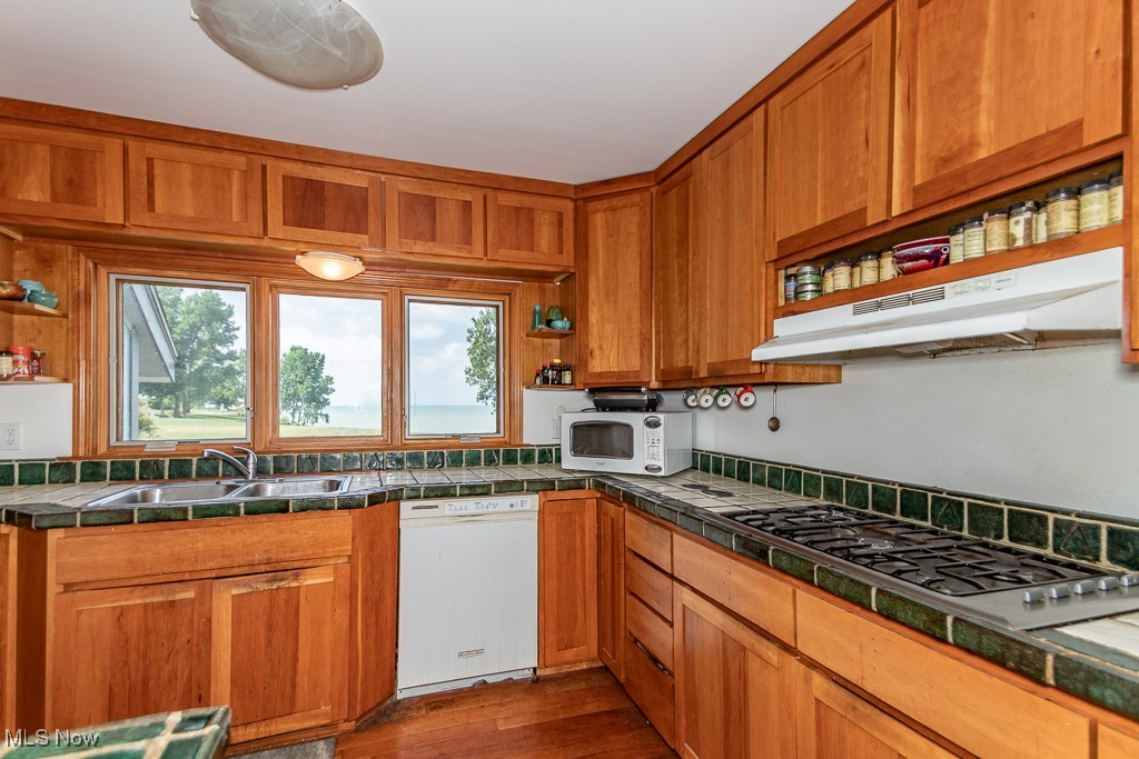 7563 Salida Road Mentor, OH 44060 - Photo 7 of 48 Kitchen featuring white appliances, brown cabinetry, under cabinet range hood, tile countertops, and dark wood finished floors