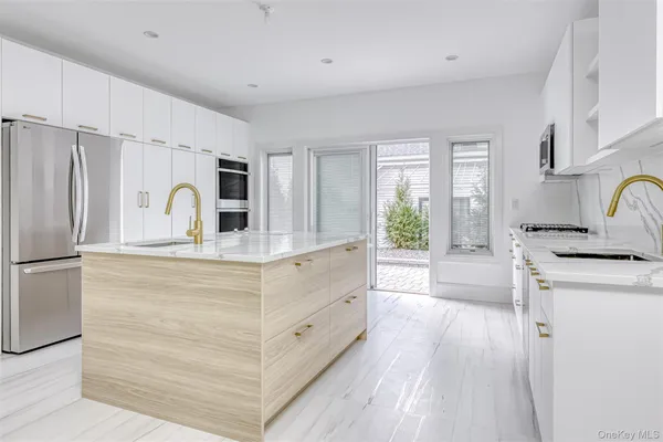a kitchen with sink a refrigerator and white cabinets with wooden floor