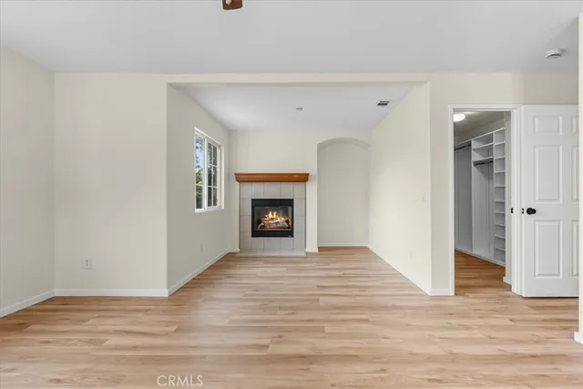 a view of an empty room with wooden floor and a fireplace