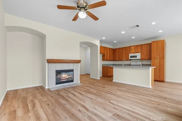 a view of a kitchen and an empty room with wooden floor a fireplace