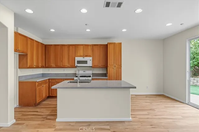 a kitchen with stainless steel appliances granite countertop a sink a stove a refrigerator cabinets and wooden floor