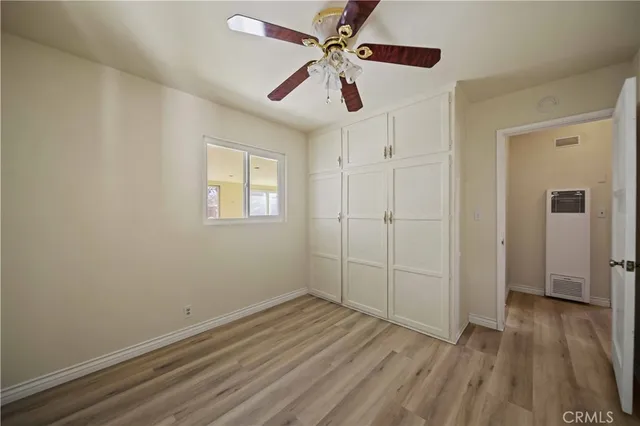 an empty room with wooden floor ceiling fan and windows