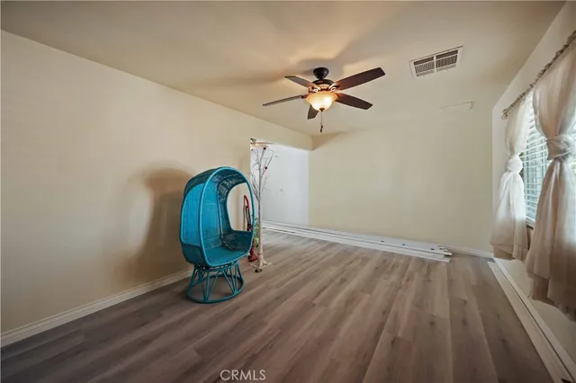 a view of a room with wooden floor and a ceiling fan
